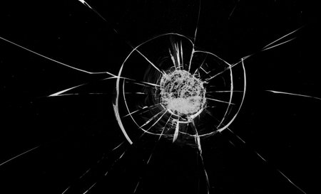 Round cracks in glass on black background. The hole in the glass surface from the bullet.