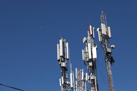 Many mobile towers, satellites and repeaters on a background of blue sky. Wireless communication equipment.の写真素材