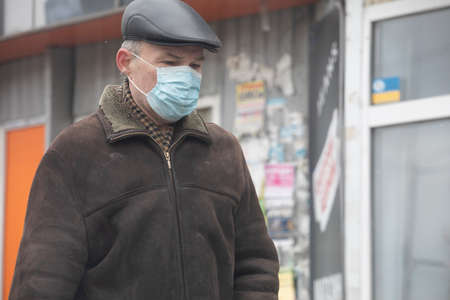 Ukraine Kiev March 23, 2020: A man walking down the street wore a hat and mask to protect against COVID-19のeditorial素材