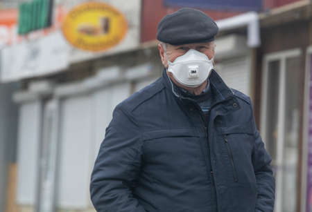 Ukraine Kiev March 23, 2020: A man walking down the street wore a hat and mask to protect against COVID-19のeditorial素材