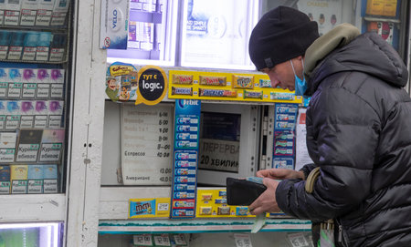 Ukraine Kiev March 23: The guy buys cigarettes in a kiosk by removing his mask, exposing himself to...