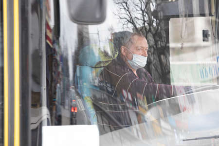 Ukraine Kiev March 23: Bus driver in medical mask. Quarantine measures against the spread of SARS-CoV-2 or COVID-19 coronaviruses.のeditorial素材