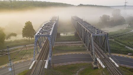 A railway bridge in the morning fog or smoke through which the rays of the sun shine background.の写真素材