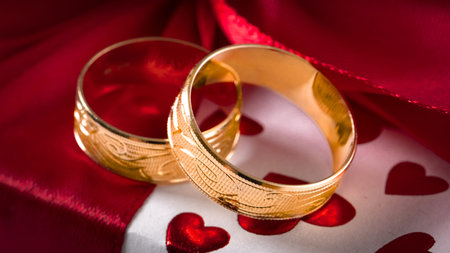 Two gold wedding rings with a thread on a red gift box. Selective focus.