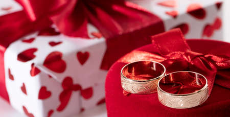 Two gold wedding rings with a thread on a red gift box. Selective focus.の写真素材