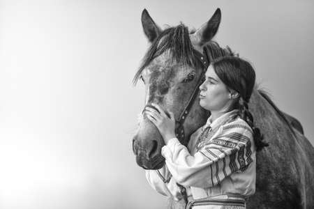 Young attractive white woman in noble clothes stroking a horse.の写真素材