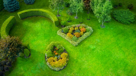 A lawn in Mezhyhirya Park, a beautiful green lawn, a hedge of evergreen plants, and colorful flower beds.の写真素材