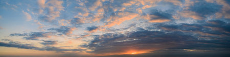 Panorama of the morning blue sky, illuminated by orange and red sunlight, colorful dawn.