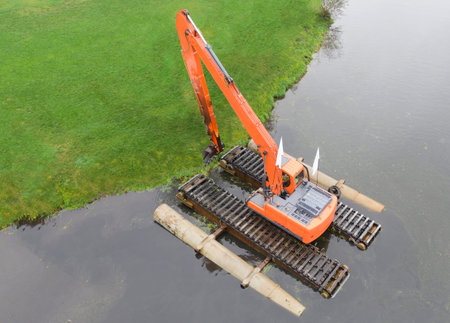 Floating excavator for cleaning ponds, aerial view. Provision of water treatment services.