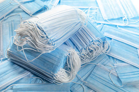 Many medical disposable blue mask, two stacks on a white background mask for protection against virusの写真素材
