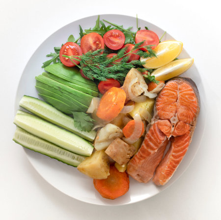 plate of healthy food fried fish, salmon, salad on a white plate. on a white marble background.