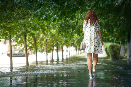 A young woman walks down the street during the summer rain.の写真素材