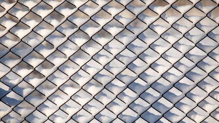 Metal mesh is covered with snow. Winter backgroundの写真素材