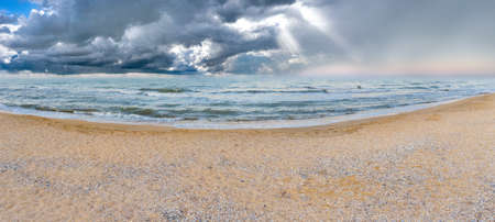 Clean beach after a thunderstorm. The sun's rays shine through the storm clouds.の写真素材