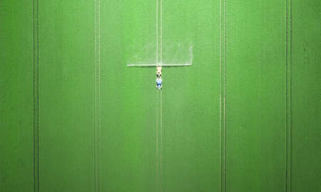 The tractor applies herbicides, pesticides or fertilizers to the green field.の写真素材