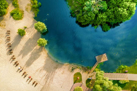 Clean warm sandy beach next to the river and green shore. Blue water, drone view.の写真素材