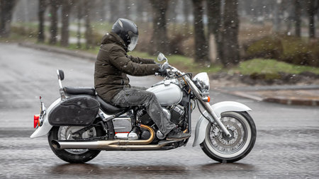 A motorcyclist in a helmet on a retro motorcycle moves down a city street.の写真素材