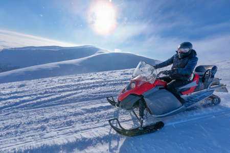 The snowmobile moves on the slope of a snow-capped mountain.の写真素材