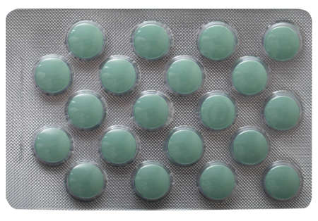 Green pills in an opaque plastic plate isolated on a white background.の写真素材
