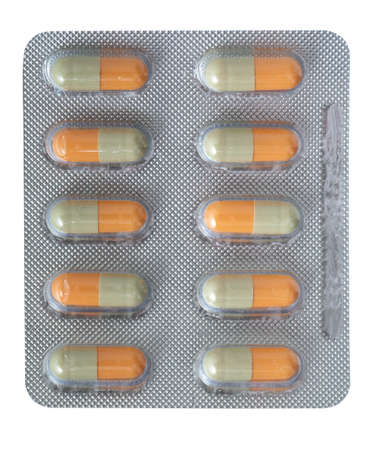 Yellow capsules in a silver plastic plate isolated on a white background.の写真素材