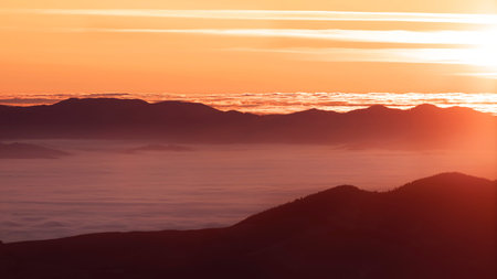 Wonderful autumn mountain landscape. Dawn with fog in the intermountains.