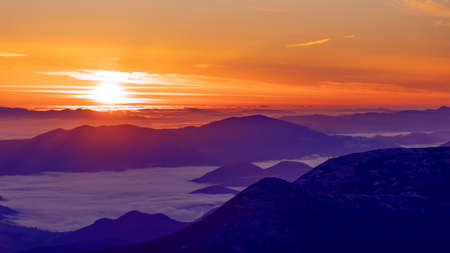 Wonderful autumn mountain landscape. Dawn with fog in the intermountains.の写真素材