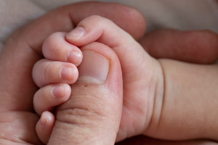 Small hand of a newborn in the big hand of an adult.