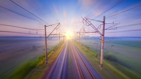 An empty railway at dawn, a light trail from a passenger train shot at long shutter speeds. Concept, travel and transportation.の写真素材
