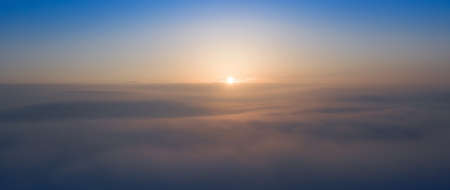 Panorama of the morning blue sky, illuminated by orange and red sunlight, colorful dawn.の写真素材