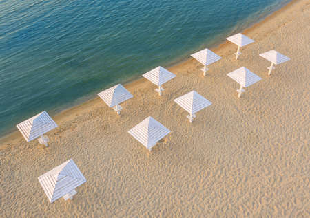 Empty clean beach on the Adriatic sea, aerial view. Wooden umbrellas for sun protection.の写真素材