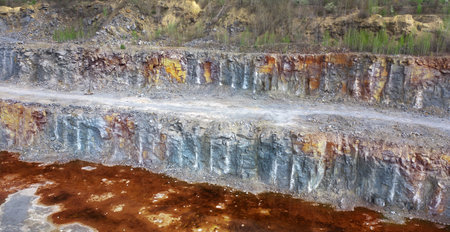 Large granite quarry with gray stone. Red water at the bottom of the quarry. Iron Ore.
