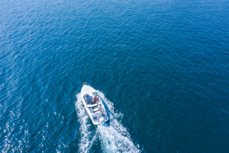 A high-speed yacht maneuvers on the surface of the water. Holidays at sea or in the ocean, rental of sea vessels. Water sports.の写真素材