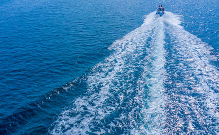 A high-speed yacht maneuvers on the surface of the water. Holidays at sea or in the ocean, rental of sea vessels. Water sports.の写真素材
