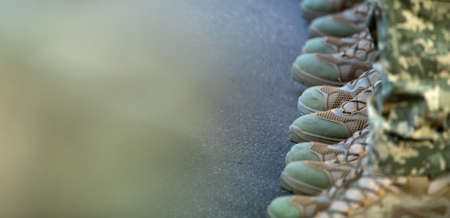 The soldiers' legs are dressed in ankle boots and camouflage pants. Close-up, selective focus.の写真素材