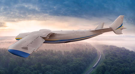 A large passenger plane flies over the railway and train.の写真素材