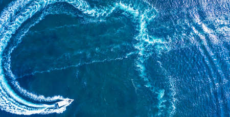 A high-speed yacht maneuvers on the surface of the water. Holidays at sea or in the ocean, rental of sea vessels. Water sports.の写真素材