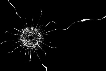 Cracks in the window. Bullet hole in the glass. Isolated on a black background.の写真素材