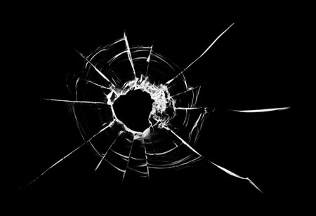 Cracks in the window. Bullet hole in the glass. Isolated on a black background.の写真素材