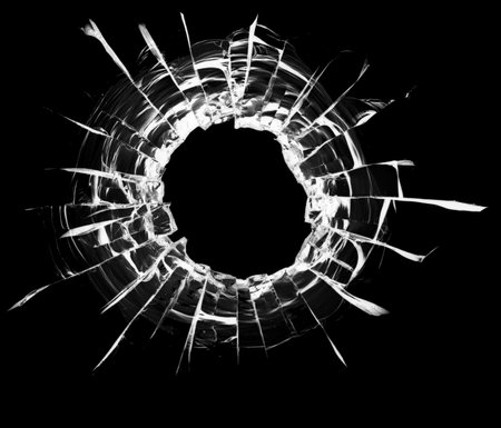 Cracks in the window. Bullet hole in the glass. Isolated on a black background.の写真素材