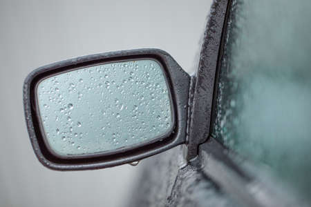 The black mirror of the car is covered with drops of water or ice.の写真素材