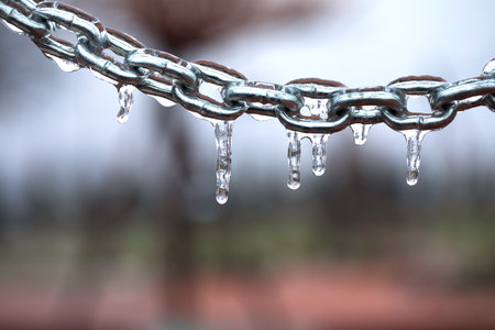 Icicles on a chain, frosted metal on a light background.の写真素材