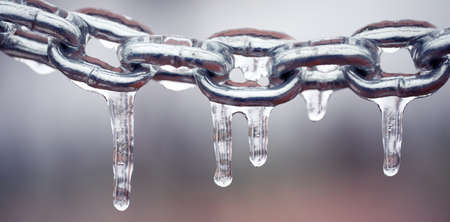 Icicles on a chain, frosted metal on a light background.の写真素材
