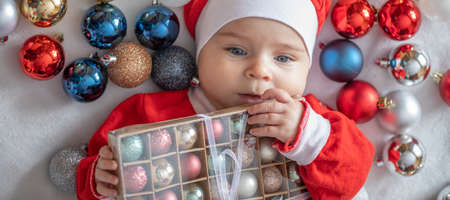 Toddler in a suit of Santa Claus with Christmas tree decorations.の写真素材