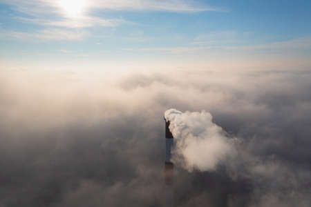 Plant pipe high above the clouds. Harmful emissions into the upper atmosphere. Climate change due to the combustion of carbon fuel.の写真素材