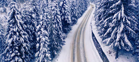 Aerial view of a curved mountain road Aerial view of a curved mountain road in Europe. winter mountain landscape. Snow-covered trees and mountain slopes. Drone view.Europe.の写真素材