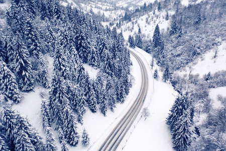 Aerial view of a curved mountain road Aerial view of a curved mountain road in Europe. winter mountain landscape. Snow-covered trees and mountain slopes. Drone view.Europe.の写真素材