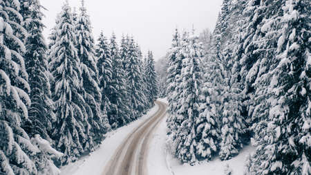 Aerial view of a curved mountain road Aerial view of a curved mountain road in Europe. winter mountain landscape. Snow-covered trees and mountain slopes. Drone view.Europe.の写真素材