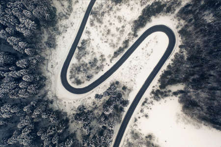 Aerial view of a curved mountain road Aerial view of a curved mountain road in Europe. winter mountain landscape. Snow-covered trees and mountain slopes. Drone view.Europe.の写真素材