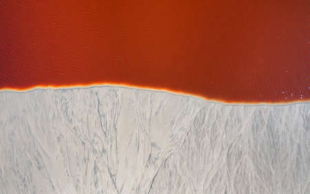 Traces of erosion on sand texture. top view Traces of erosion on sand texture. red water. Pollution of the reservoir by chemical products.の写真素材