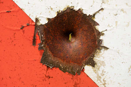 Bullet hole in old metal painted red. abstract background.の写真素材